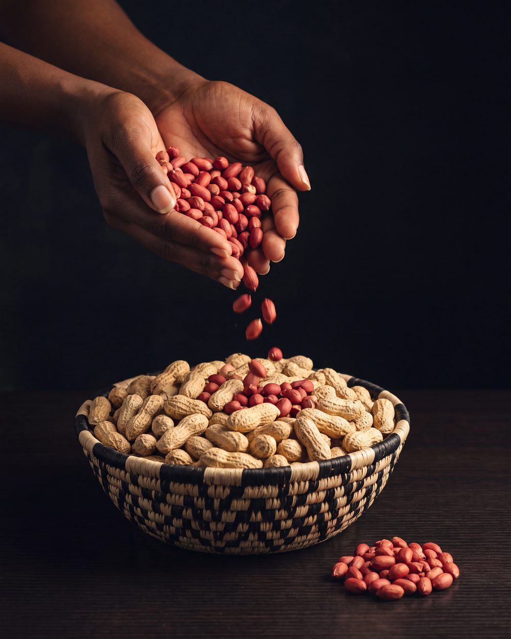 Photo de mains versant des arachides dans un panier tressé, l'arachide du mafé, épicerie africaine Sepela à Lyon 7